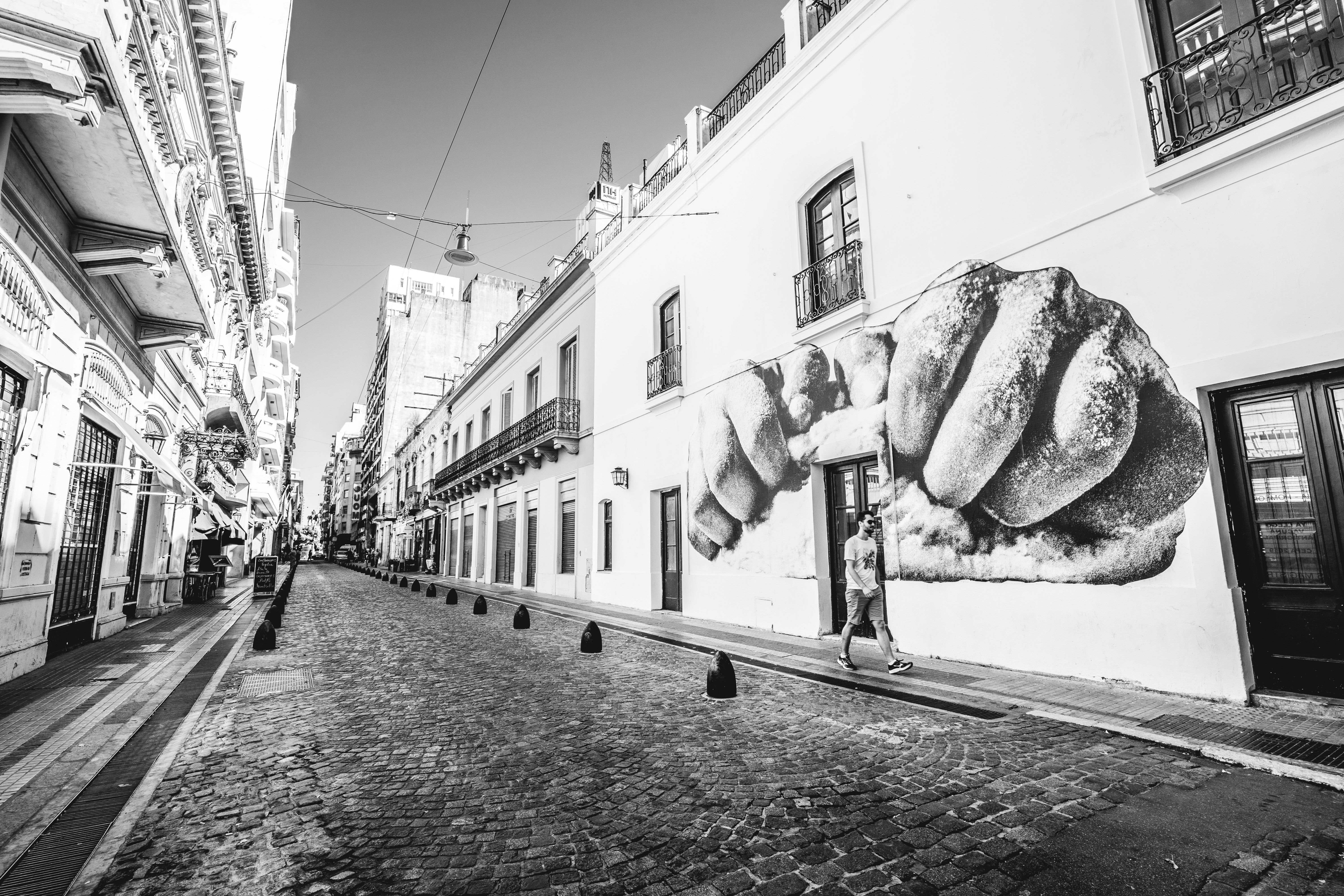 grayscale photography of man walking on sidewalk